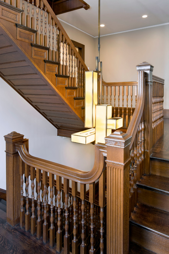 Пример оригинального дизайна: большая п-образная деревянная лестница в викторианском стиле с деревянными ступенями и деревянными перилами