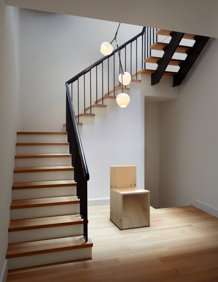 Cette image montre un escalier design avec des marches en bois et un garde-corps en métal.