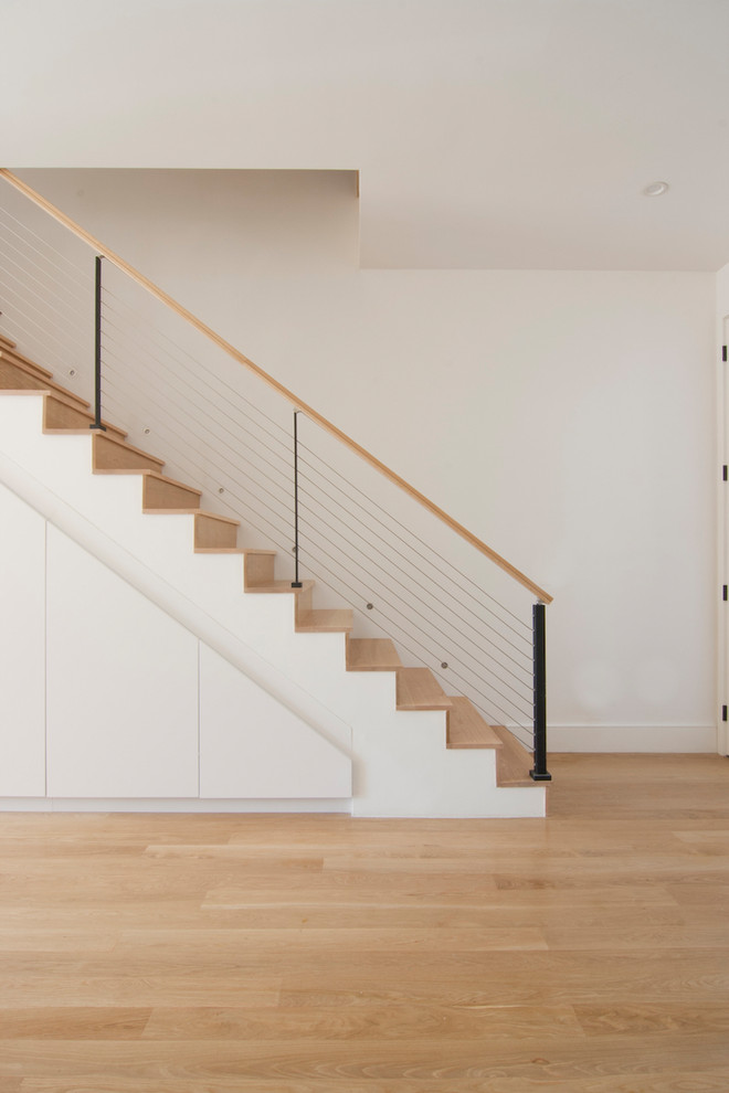 Diseño de escalera recta moderna de tamaño medio con escalones de madera, contrahuellas de madera y barandilla de cable
