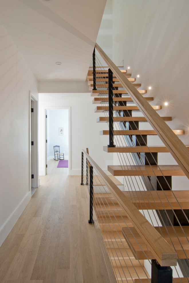 Diseño de escalera suspendida actual de tamaño medio sin contrahuella con escalones de madera y barandilla de cable