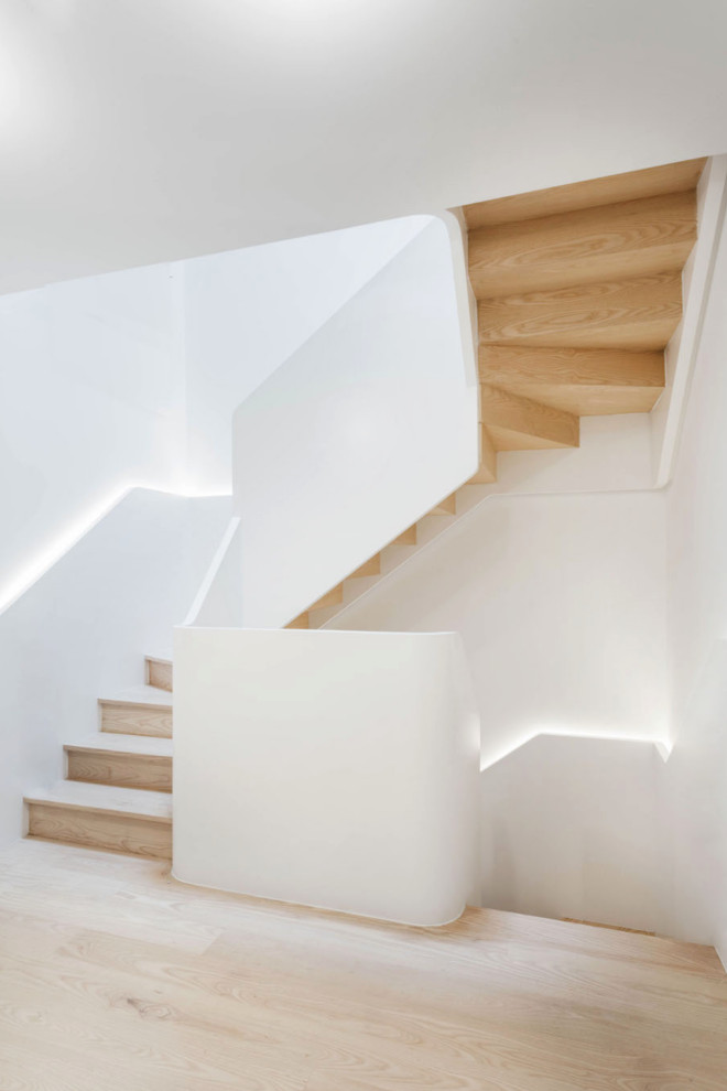Ejemplo de escalera curva minimalista de tamaño medio con escalones de madera, contrahuellas de madera y barandilla de madera