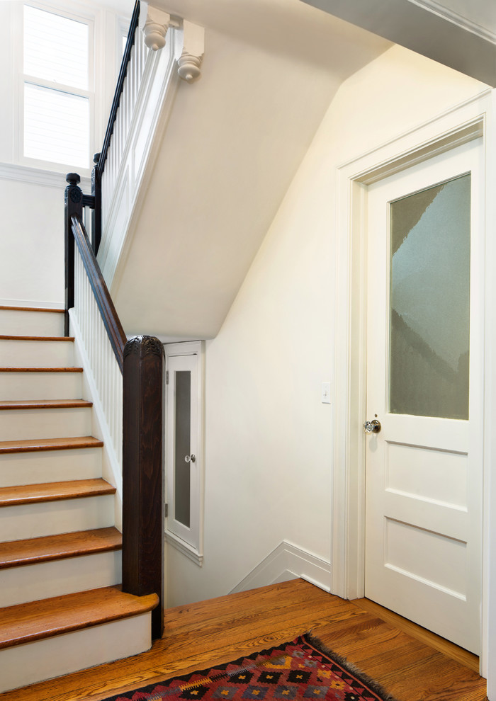 This is an example of a medium sized shabby-chic style wood u-shaped staircase in New York with painted wood risers.