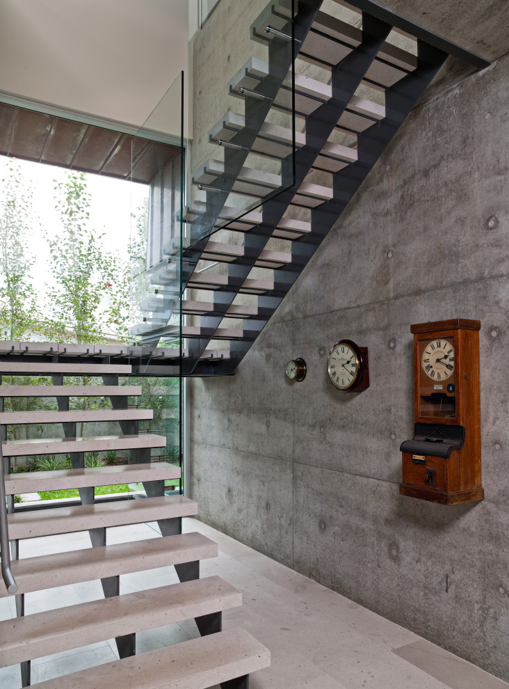 Imagen de escalera suspendida minimalista pequeña con escalones de piedra caliza, contrahuellas de piedra caliza y barandilla de vidrio
