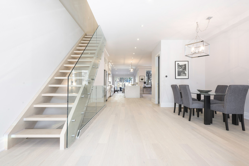 Стильный дизайн: прямая лестница среднего размера в стиле модернизм с деревянными ступенями и стеклянными перилами без подступенок - последний тренд