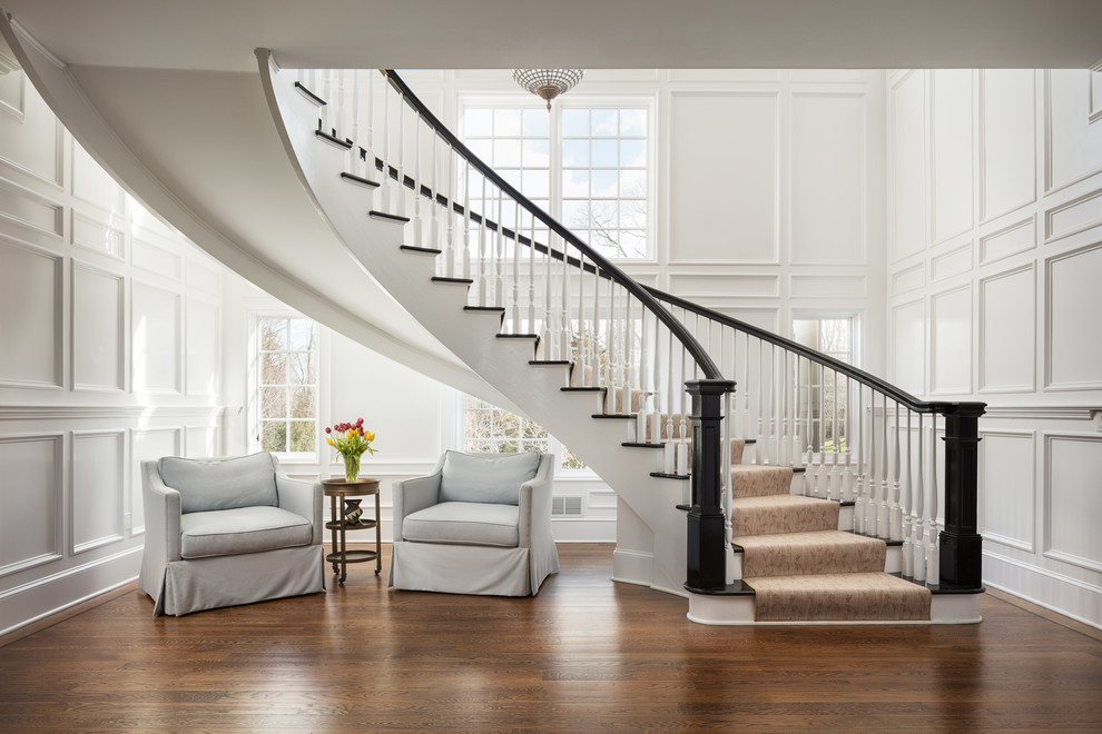 На фото: изогнутая лестница в классическом стиле с деревянными ступенями и деревянными перилами без подступенок с