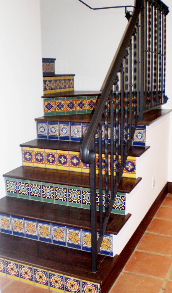 Diseño de escalera en L mediterránea de tamaño medio con escalones de madera y contrahuellas con baldosas y/o azulejos