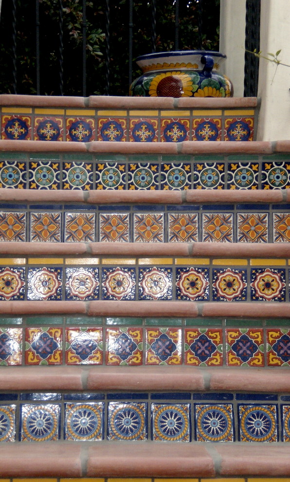 На фото: маленькая изогнутая лестница в средиземноморском стиле с ступенями из плитки и подступенками из плитки для на участке и в саду