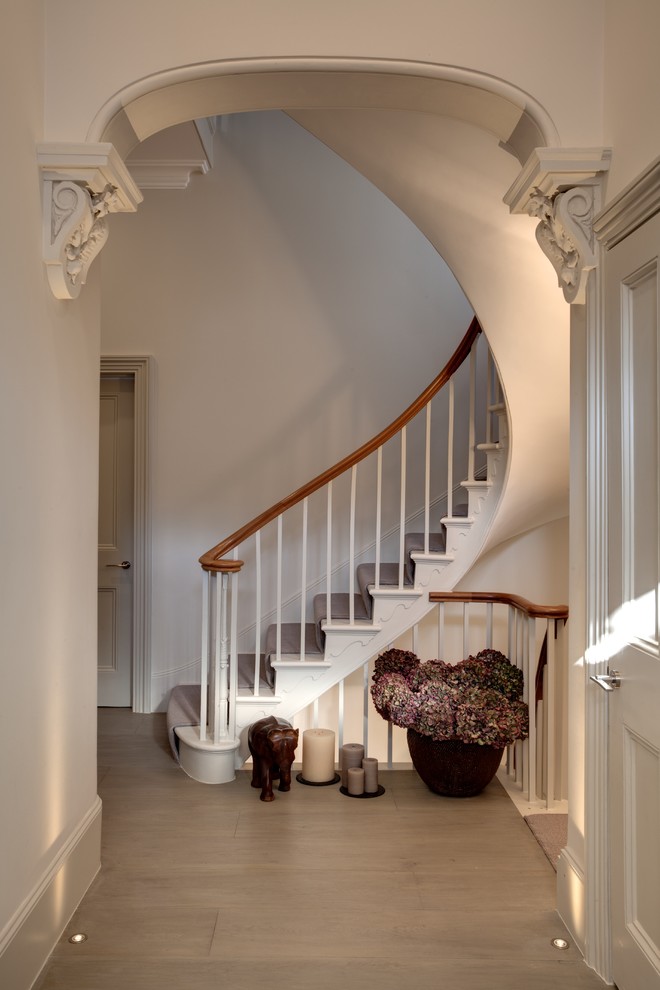 This is an example of a traditional painted wood curved staircase in London with painted wood risers.