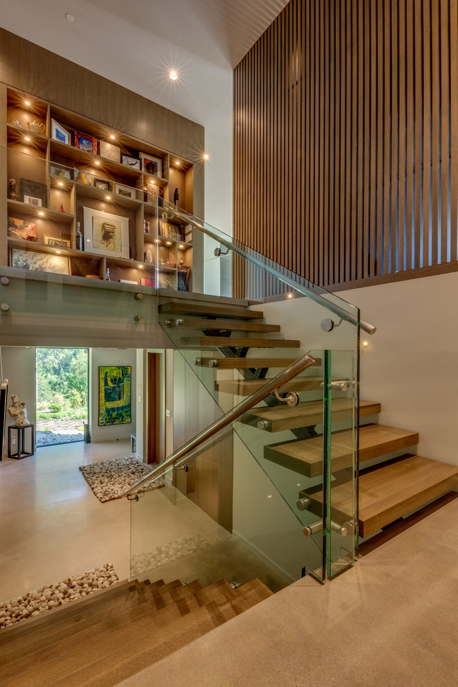 На фото: изогнутая деревянная лестница среднего размера в современном стиле с деревянными ступенями и перилами из смешанных материалов с