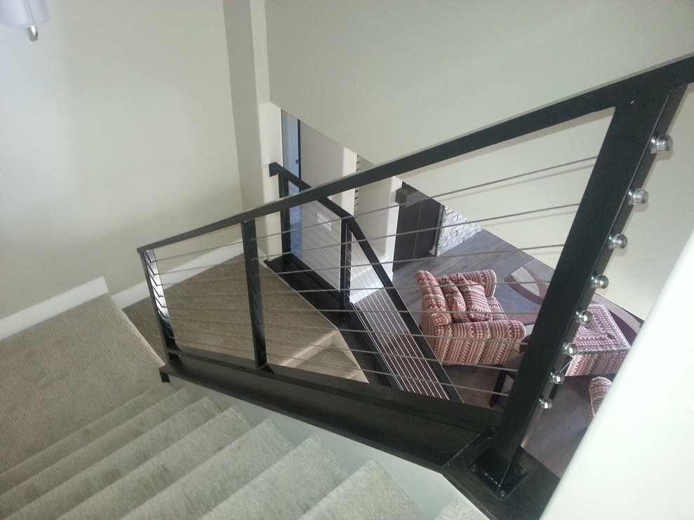 Пример оригинального дизайна: большая п-образная лестница в стиле модернизм с ступенями с ковровым покрытием, ковровыми подступенками и перилами из тросов
