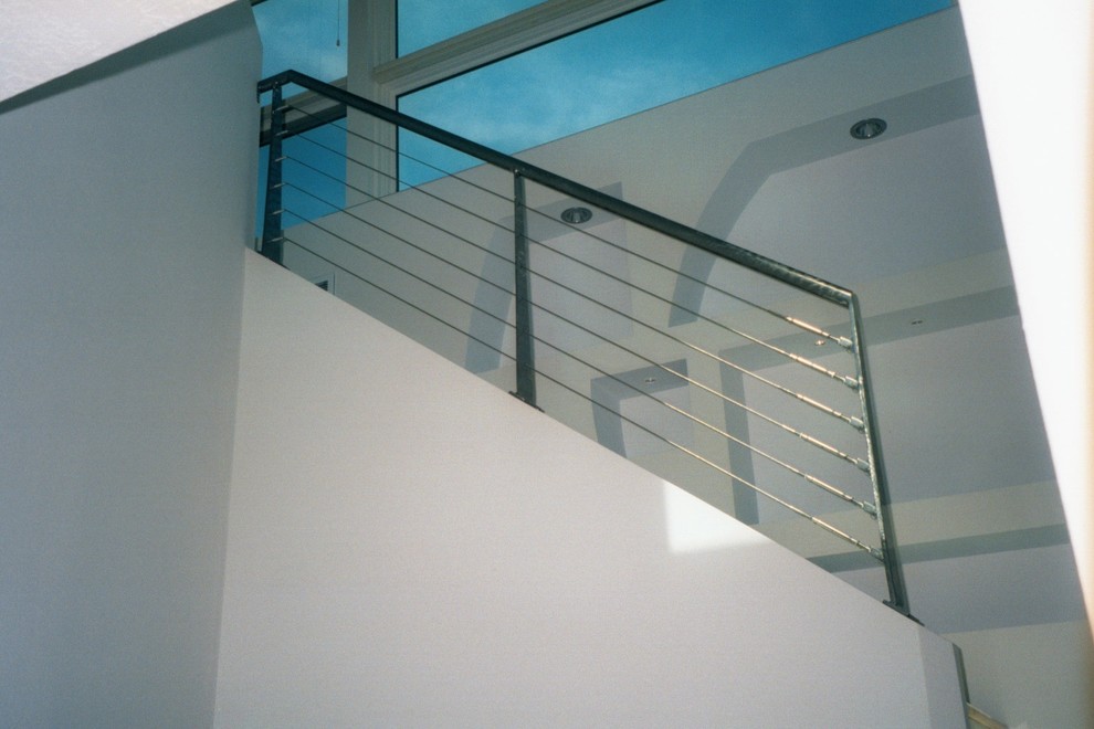 Idée de décoration pour un escalier design en L avec des marches en bois et un garde-corps en métal.