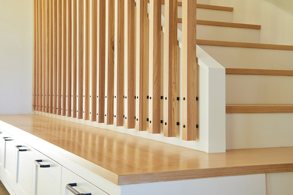 На фото: п-образная лестница в стиле неоклассика (современная классика) с деревянными ступенями, крашенными деревянными подступенками и металлическими перилами