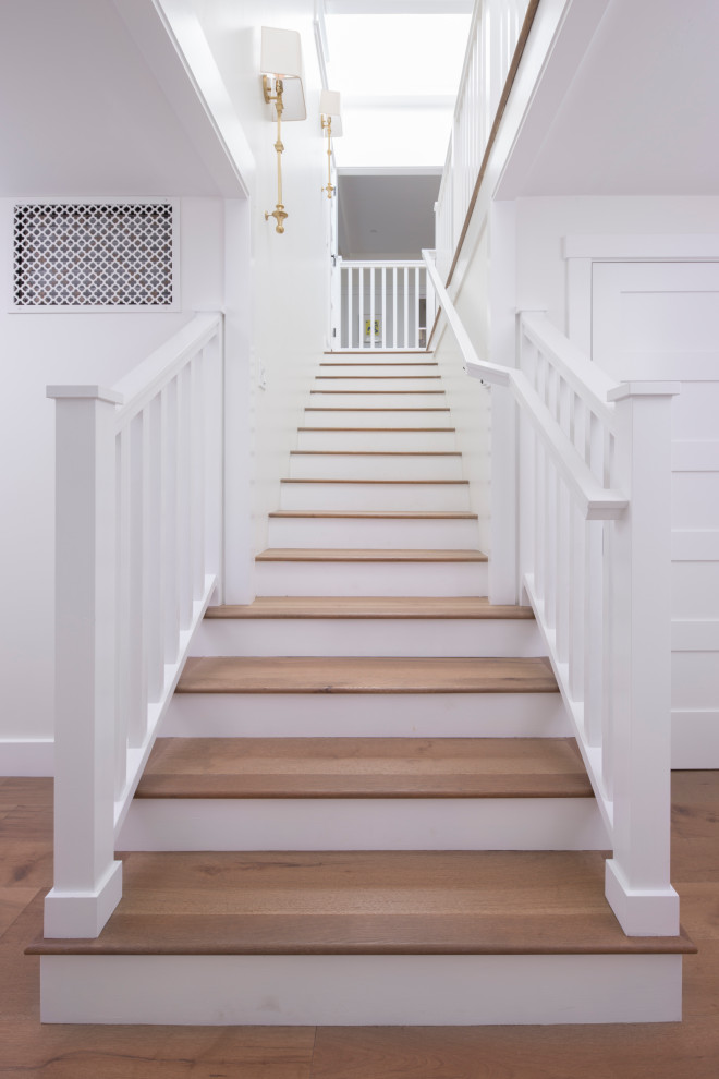 На фото: п-образная лестница в морском стиле с деревянными ступенями, крашенными деревянными подступенками и деревянными перилами