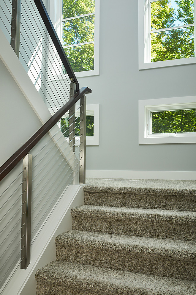 Стильный дизайн: п-образная лестница в стиле модернизм с ступенями с ковровым покрытием, ковровыми подступенками и перилами из смешанных материалов - последний тренд