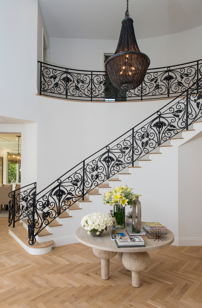 Свежая идея для дизайна: изогнутая лестница в стиле неоклассика (современная классика) с деревянными ступенями и металлическими перилами без подступенок - отличное фото интерьера
