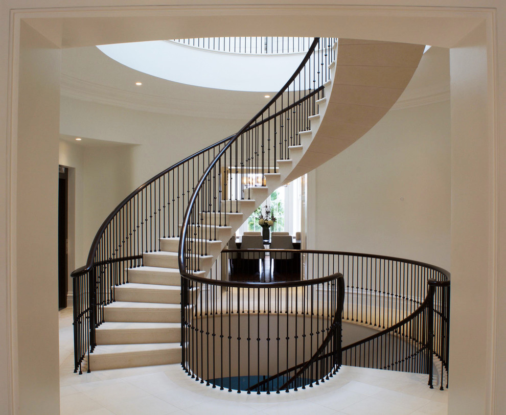 Idées déco pour un escalier courbe contemporain de taille moyenne avec des marches en pierre calcaire, des contremarches en pierre calcaire et un garde-corps en métal.