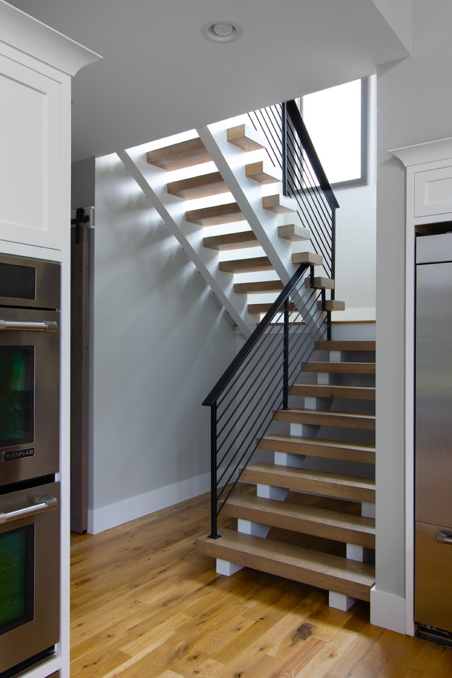 Diseño de escalera suspendida de estilo de casa de campo grande con escalones de madera y barandilla de metal