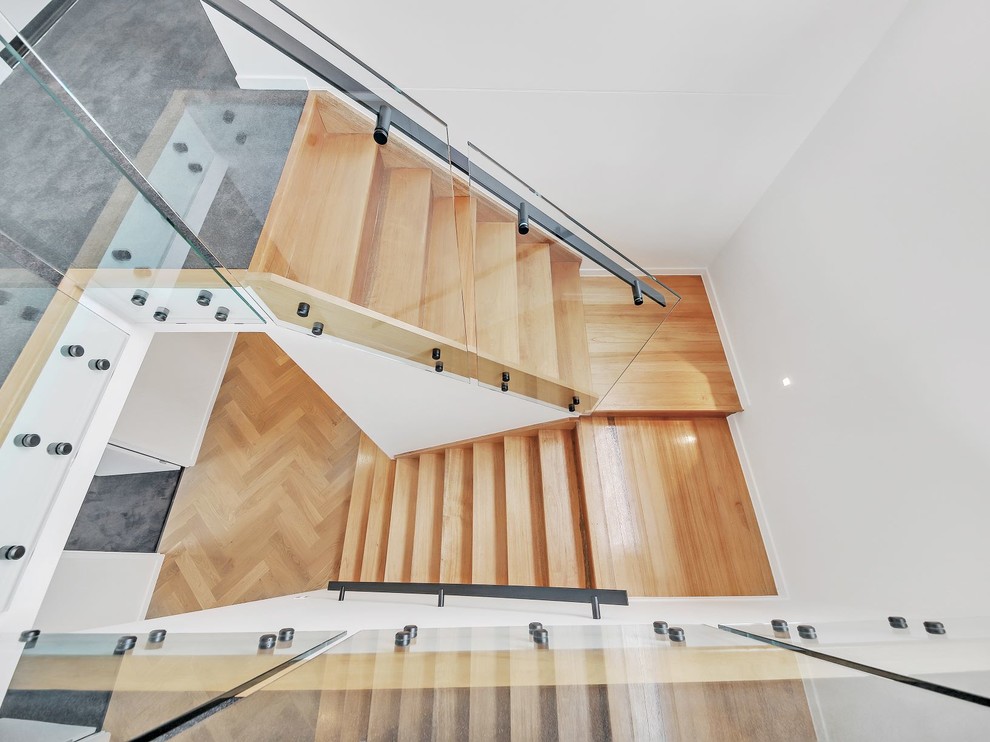 This is an example of a medium sized contemporary wood u-shaped glass railing staircase in Brisbane with wood risers.