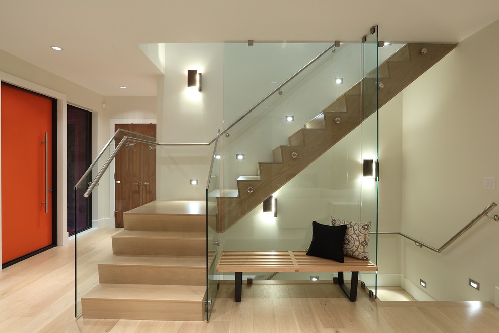 Aménagement d'un grand escalier contemporain en L avec des marches en bois, des contremarches en bois et un garde-corps en verre.