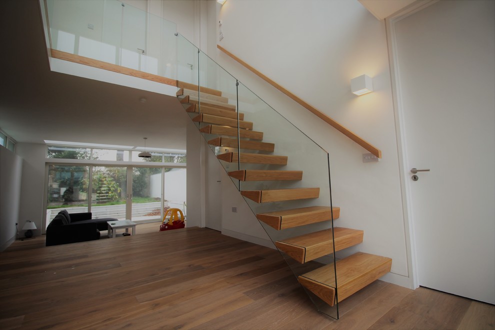 Ejemplo de escalera suspendida moderna de tamaño medio sin contrahuella con escalones de madera y barandilla de vidrio