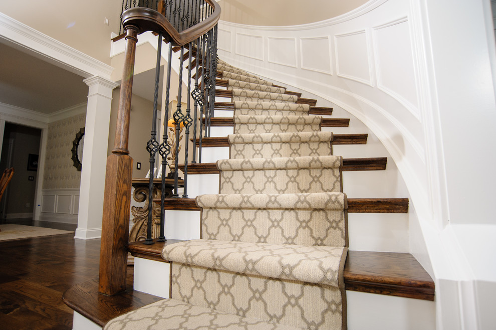 Photo of a classic wood curved staircase in Detroit with carpeted risers.