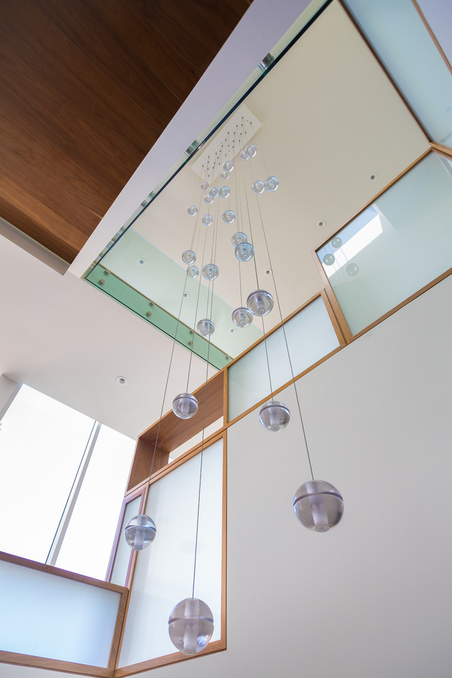 Huge trendy wooden floating glass railing staircase photo in Los Angeles