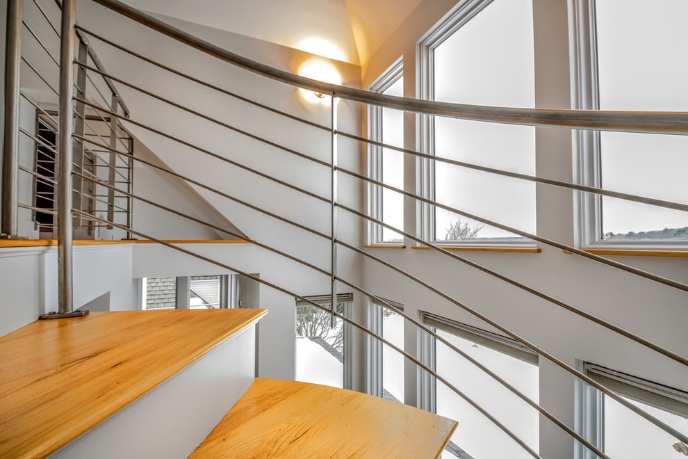 На фото: изогнутая лестница среднего размера в современном стиле с деревянными ступенями и крашенными деревянными подступенками с