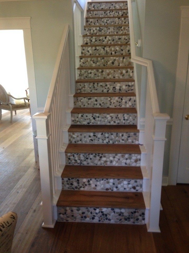 Diseño de escalera recta costera grande con escalones de madera, contrahuellas con baldosas y/o azulejos y barandilla de madera