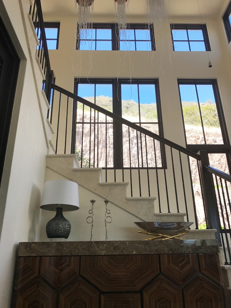 На фото: большая угловая лестница в стиле неоклассика (современная классика) с металлическими перилами, ступенями из плитки и подступенками из плитки