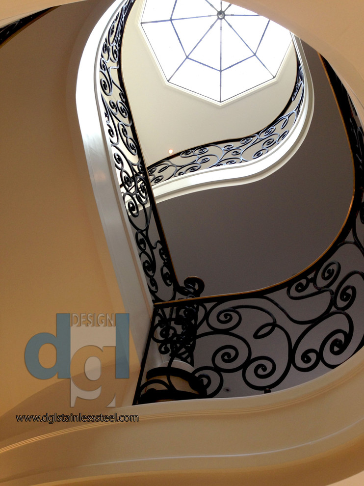 Imagen de escalera curva moderna grande con escalones de mármol, contrahuellas de mármol y barandilla de metal