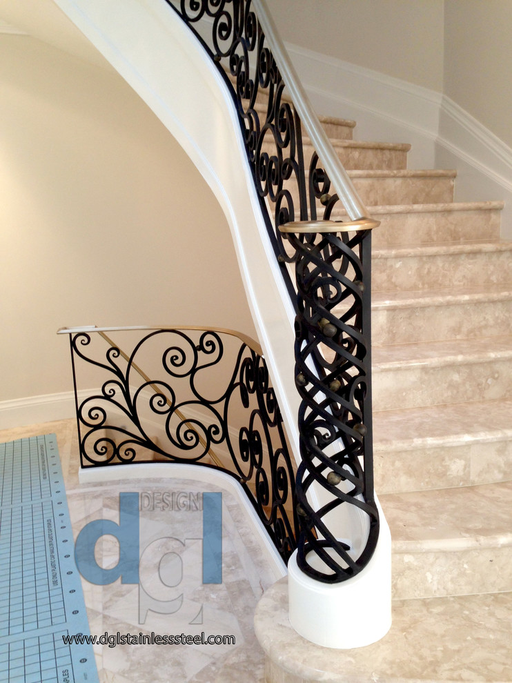 This is an example of a large modern curved metal railing staircase in Toronto with marble treads and marble risers.