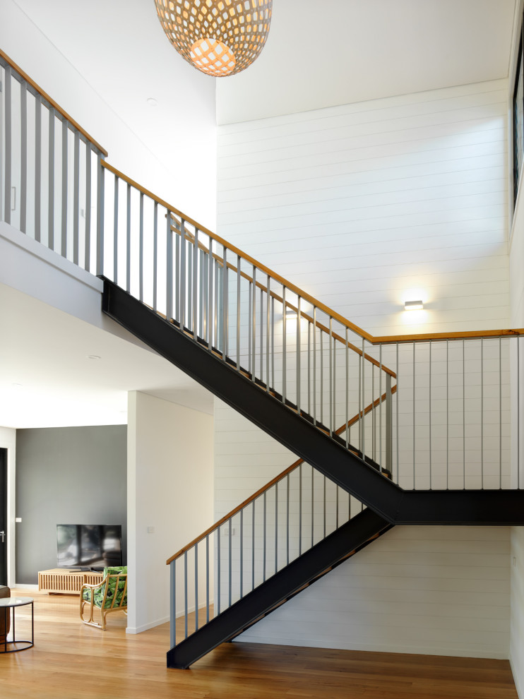 Idée de décoration pour un grand escalier design en U avec des marches en bois et un garde-corps en métal.