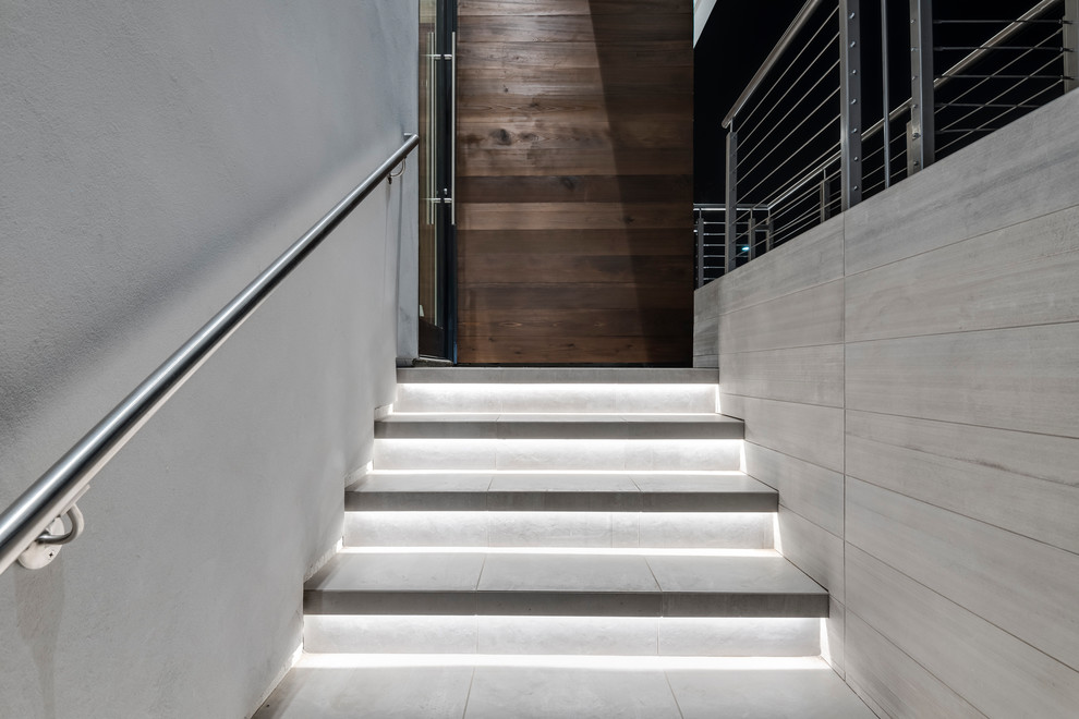 Mittelgroße Moderne Treppe in L-Form mit gefliesten Treppenstufen, gefliesten Setzstufen und Stahlgeländer in San Diego