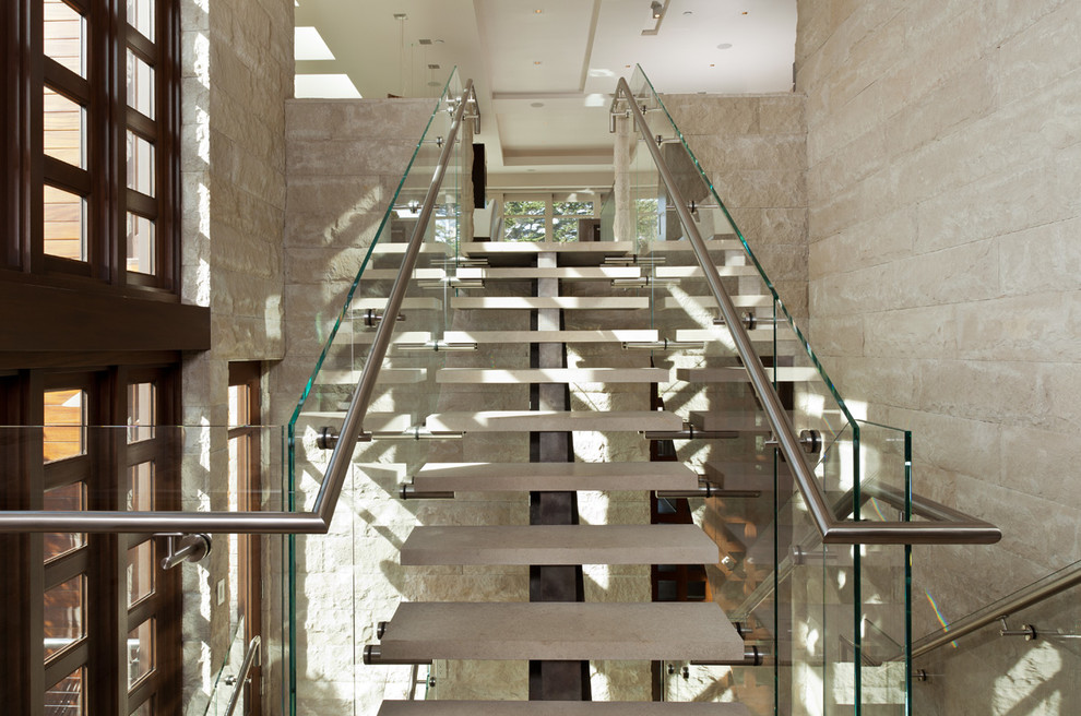 На фото: угловая лестница среднего размера в современном стиле с ступенями из известняка и стеклянными перилами без подступенок с