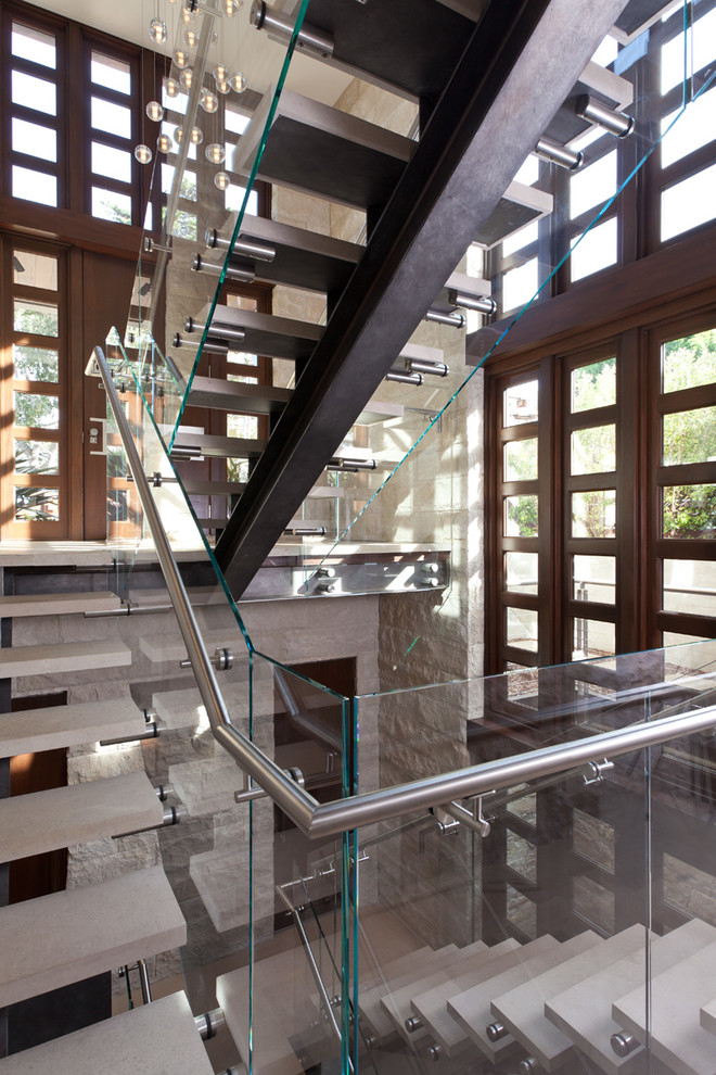 Exempel på en mellanstor modern l-trappa i kalk, med öppna sättsteg och räcke i glas