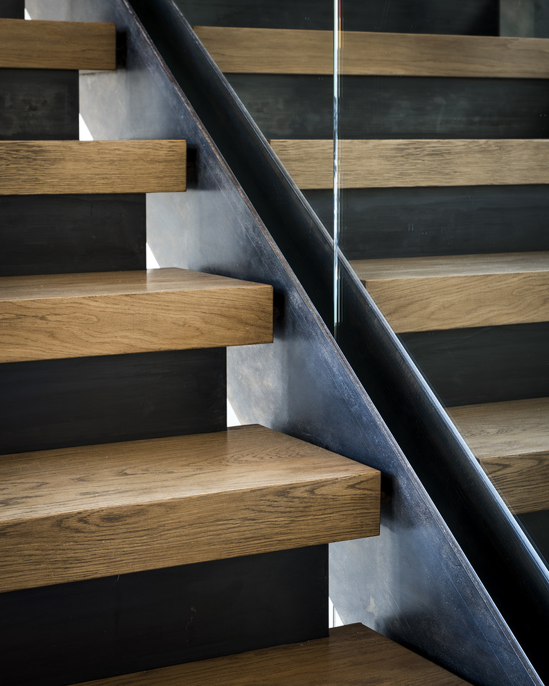 Ejemplo de escalera recta moderna con escalones de madera, contrahuellas de hormigón y barandilla de vidrio