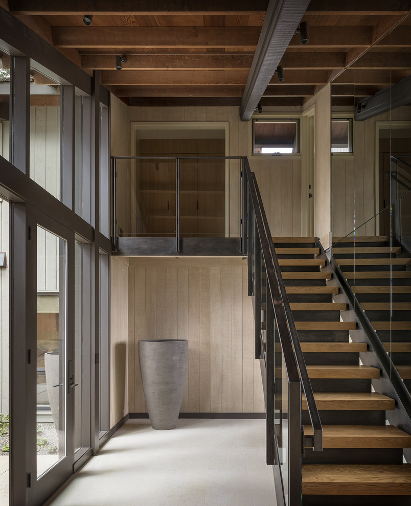 Foto de escalera recta moderna con escalones de madera, contrahuellas de hormigón y barandilla de vidrio