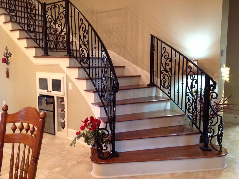Imagen de escalera curva clásica grande con escalones de madera, contrahuellas de madera pintada y barandilla de metal