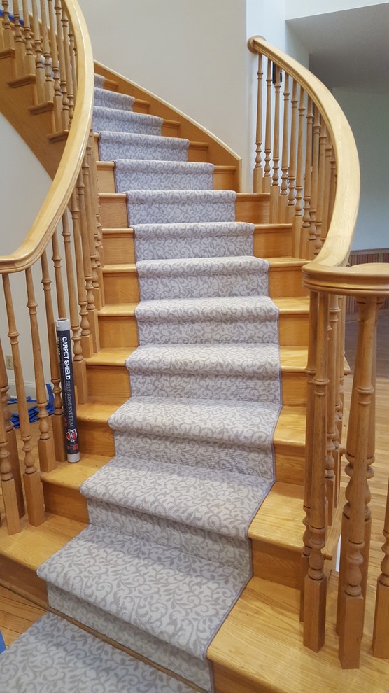 This is an example of a large classic wood curved staircase in Boston with wood risers.