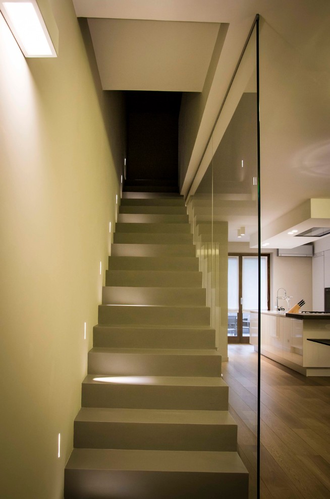 Ejemplo de escalera recta minimalista de tamaño medio con escalones de hormigón, contrahuellas de hormigón y barandilla de vidrio