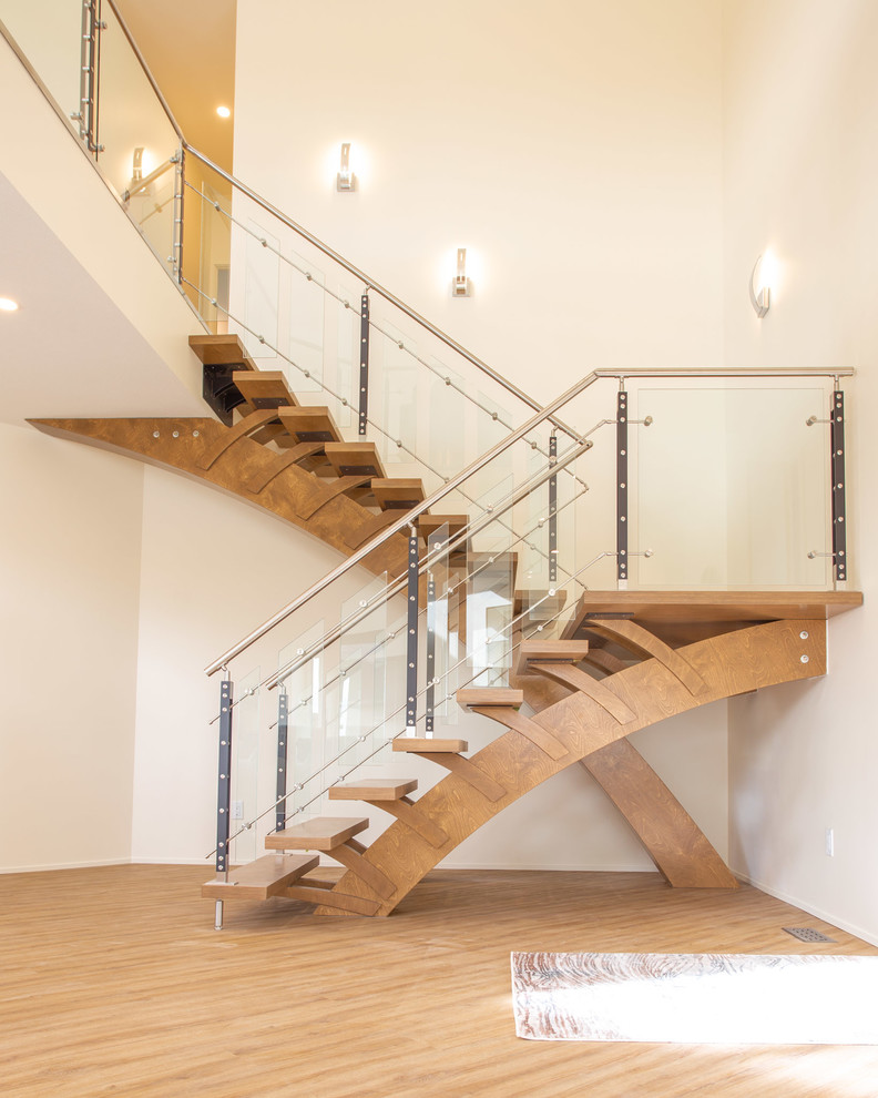 Cette image montre un escalier design en U avec des marches en bois, des contremarches en bois et un garde-corps en verre.