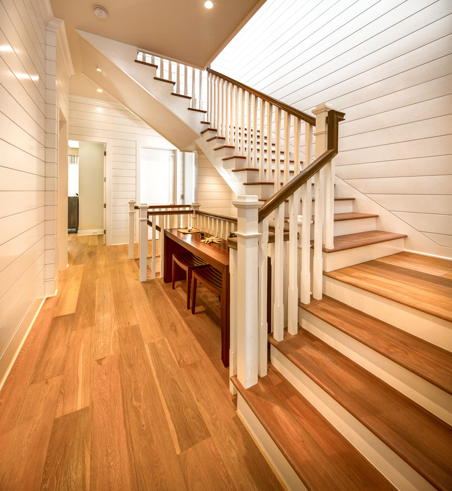 Пример оригинального дизайна: изогнутая лестница среднего размера в морском стиле с деревянными ступенями, крашенными деревянными подступенками и деревянными перилами