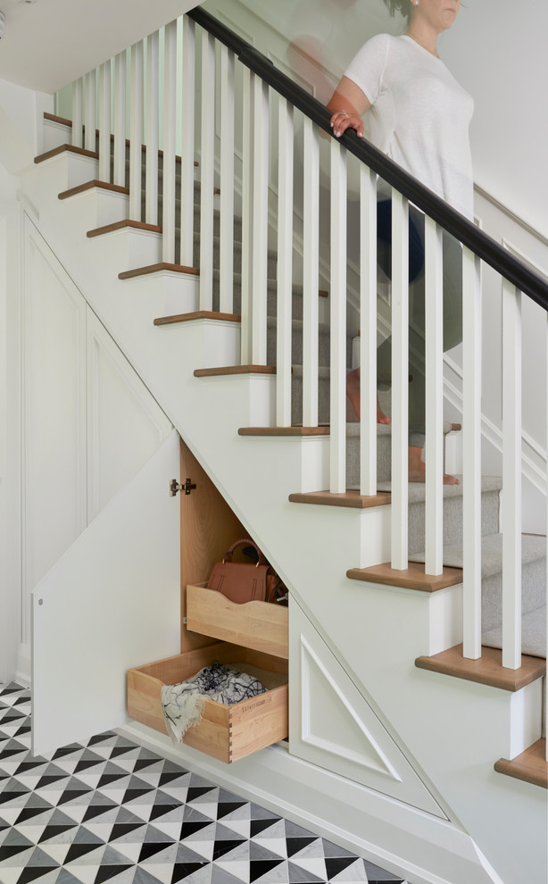 This is an example of a medium sized traditional wood straight wood railing staircase in Toronto with painted wood risers and under stair storage.