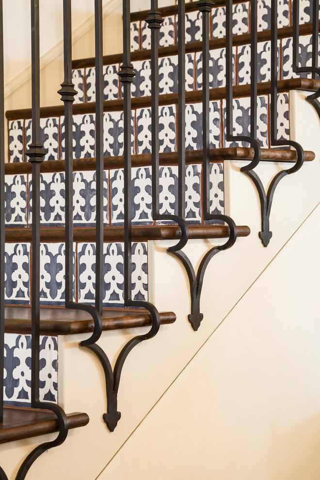 オースティンにあるラグジュアリーな中くらいなトランジショナルスタイルのおしゃれな折り返し階段 (タイルの蹴込み板、金属の手すり) の写真