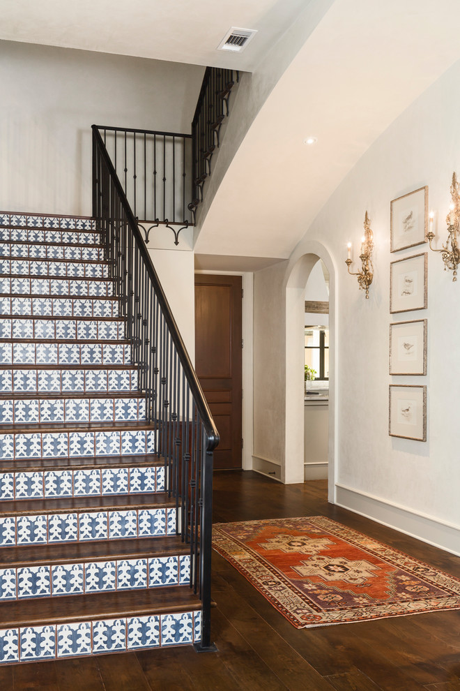 Ejemplo de escalera en U clásica renovada de tamaño medio con escalones de madera, contrahuellas con baldosas y/o azulejos y barandilla de metal