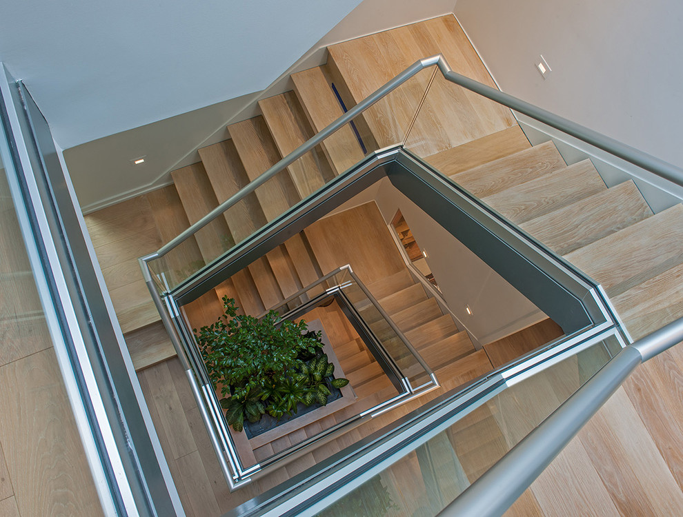 This is an example of a contemporary wood u-shaped glass railing staircase in Philadelphia with open risers.