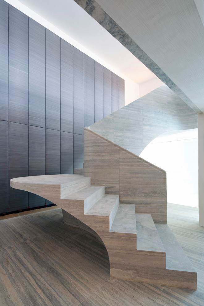 Источник вдохновения для домашнего уюта: огромная изогнутая лестница в современном стиле с ступенями из известняка и подступенками из известняка