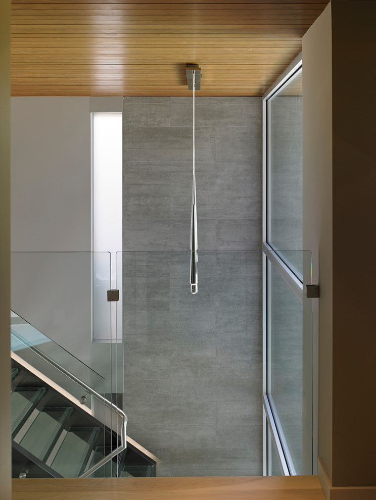 Cette image montre un grand escalier minimaliste en U avec des marches en verre.