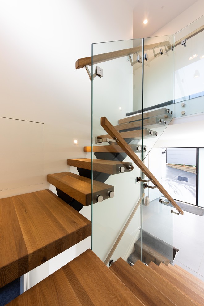 Imagen de escalera en U actual grande sin contrahuella con escalones de madera y barandilla de vidrio