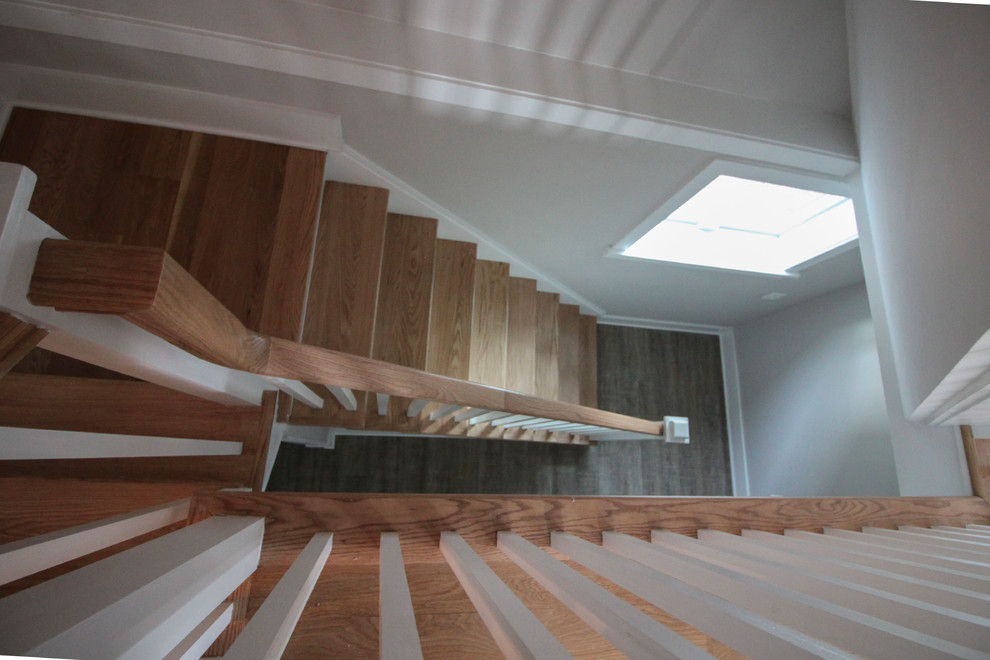 На фото: большая деревянная лестница на больцах в стиле фьюжн с деревянными ступенями и деревянными перилами
